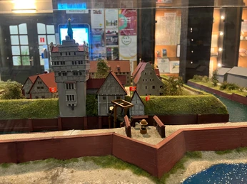 Miniaturmodell eines historischen Schlosses mit Zinnen, umgeben von Wassergräben und befestigten Mauern.