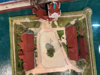 Miniaturmodell eines Schlosses mit roten Dächern, umgeben von Wassergraben und Spazierwegen.