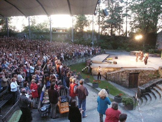 Freilichtbühne Tecklenburg Die Freilichtbühne Tecklenburg mit besetzter Zuschauertribüne während einer Abendveranstaltung.