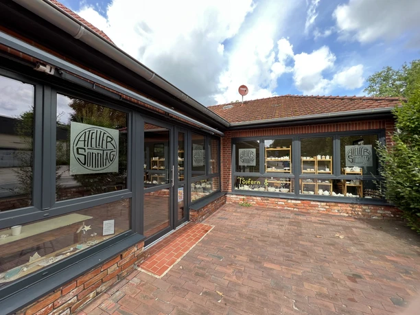 Töpferei in einem Backsteingebäude mit großen Fenstern, die kreative Keramikstücke präsentieren.