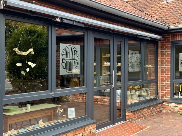 Ein modernes Gebäude mit großen Fenstern, durch die im Inneren Töpferwaren sichtbar sind.