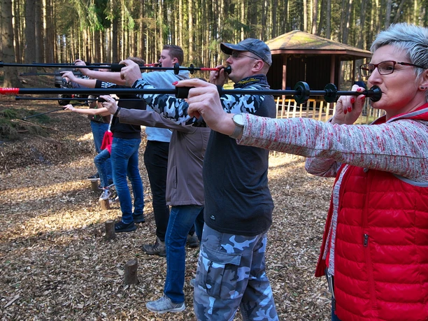 Blasrohrschießen Menschen zielen beim Blasrohrschießen im Wald, konzentriert aufgereiht vor einer Übungsfläche.