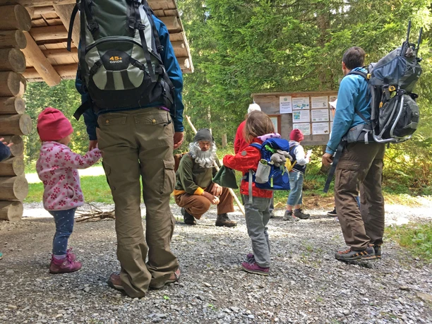 Rencontre le gentil Grimmimutz Le Grimmimutz est agenouillé sur le sol recouvert de gravier et s'adresse aux enfants et aux parents présents