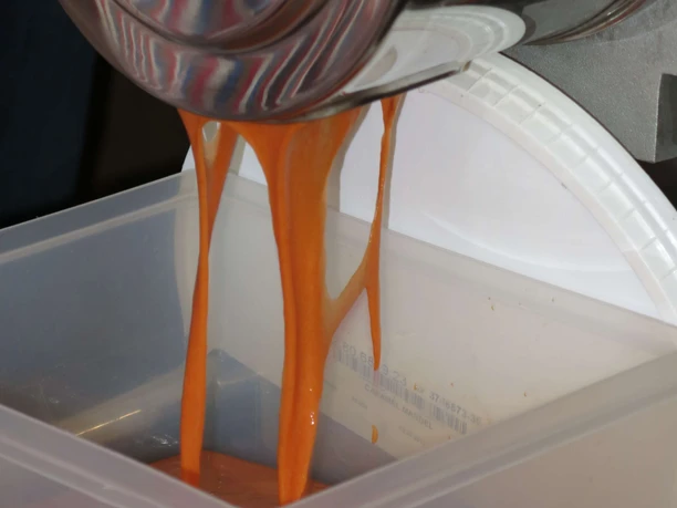 Le purée de cynorrhodon s'écoule du pressoir dans un récipient en plastique