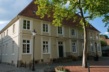 Professorenhaus Historisches zweistöckiges Gebäude mit rotem Ziegeldach und hellem Mauerwerk unter Bäumen.