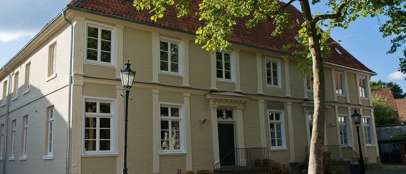 Professorenhaus Historisches zweistöckiges Gebäude mit rotem Ziegeldach und hellem Mauerwerk unter Bäumen.