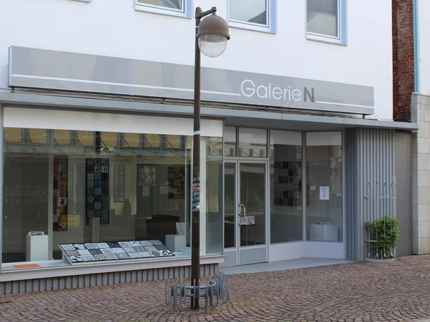 Galerie N Die Galerie N präsentiert eine moderne Glasfassade mit großen Fenstern und einer neutralen Beschilderung.