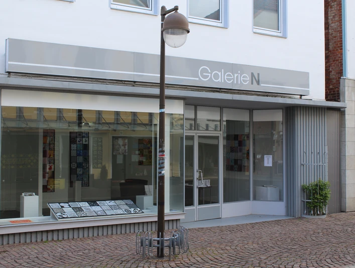 Galerie N Die Galerie N präsentiert eine moderne Glasfassade mit großen Fenstern und einer neutralen Beschilderung.