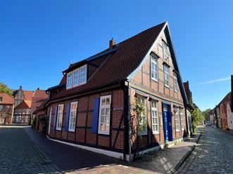 Historisches Fachwerkhaus mit blauen Fensterläden unter blauem Himmel in einem alten Stadtviertel.