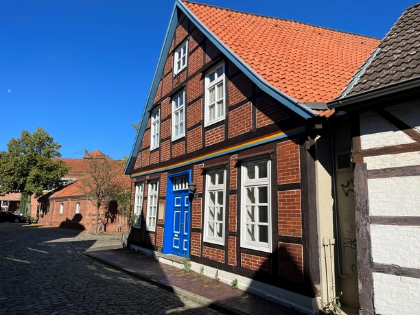 Ein traditionelles Fachwerkhaus mit hellen Fensterrahmen und einer auffälligen blauen Tür.