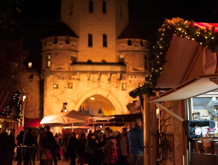 VeedelsAdvent on the Chlodwigplatz Weihnachtsmarkt bei Nacht, geschmückte Stände, rot-weiß gestreifte Dächer, beleuchtete Severinstorburg.Christmas market at night, decorated stalls, red and white striped roofs, illuminated Severinstorburg.