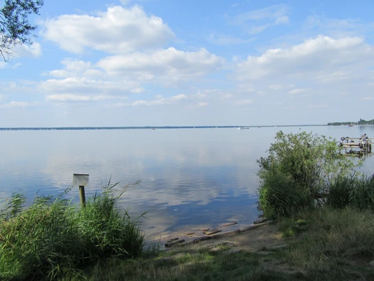 Blick über den ruhigen Steinhuder Meersee mit sanftem Wellengang und vereinzelten Booten unter blauem Himmel.
