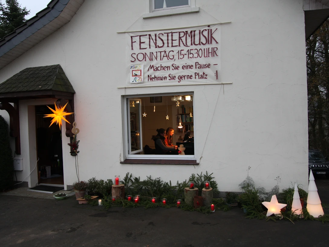 Fenstermusik - Adventsfest Eine festliche Dekoration umgibt ein Fenster, aus dem sanfte Musik tönt, mit Kerzenlichtern und Sternen.