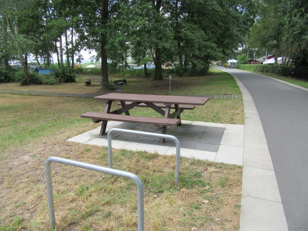 Picknickplatz Uferweg Ecke Raabeweg Mardorf Picknickplatz mit Holztisch und Bänken, umgeben von Bäumen, nahe einem asphaltierten Weg.