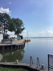 Anleger Insel Wilhelmstein Anleger mit Segelbooten und Bäumen im Hintergrund, an einem ruhigen Gewässer unter blauem Himmel.