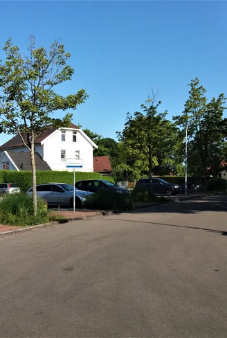 Viehmarktplatz in Apen Der Viehmarktplatz in Apen zeigt eine offene Asphaltfläche, umgeben von parkenden Autos und Bäumen.