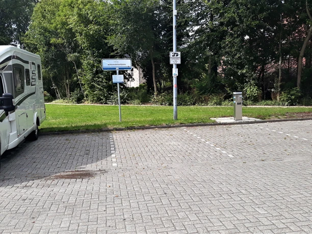 Versorgungsstelle Ein Wohnmobil steht auf einem gepflasterten Parkplatz neben einer Versorgungsstation für Strom.