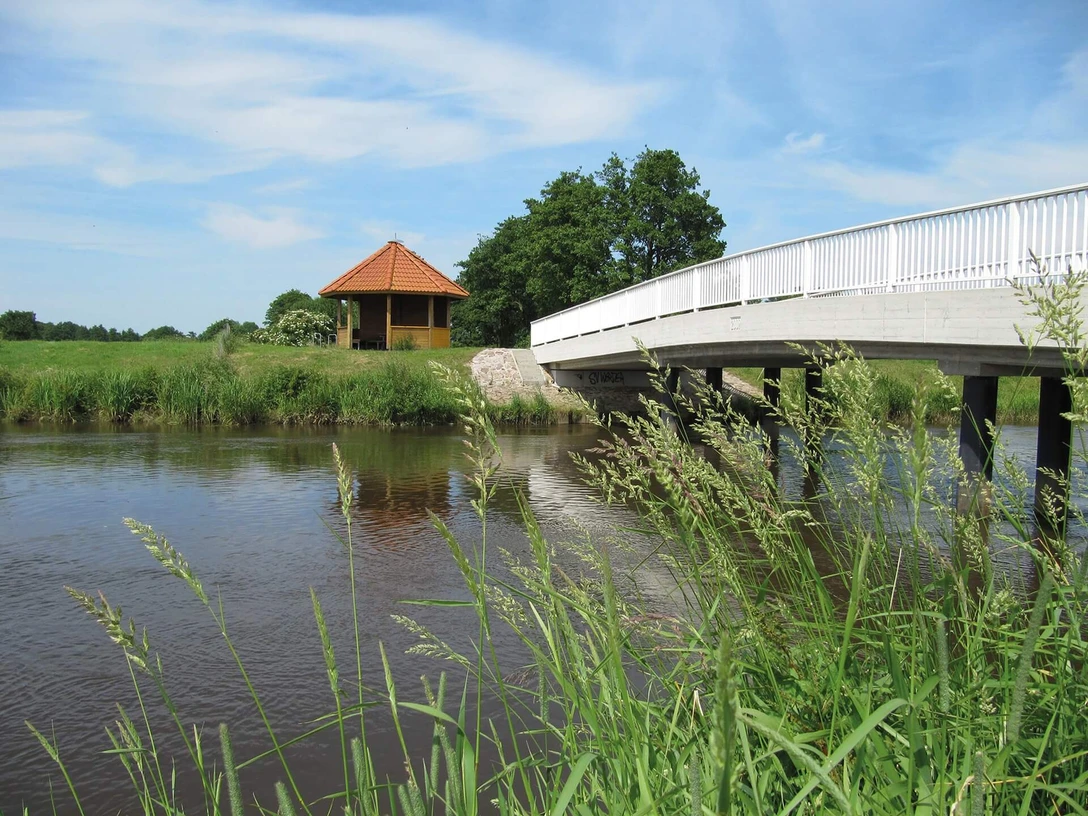 Bokeler Brücke Eine weiße Brücke überspannt das Aper Tief in einer ländlichen Umgebung. Im Hintergrund steht ein Pavillon.