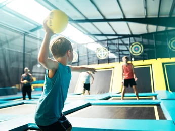 Spiele für die ganze Familie im Abenteuerland Junge beim Werfen eines Balls auf einem Trampolin in einer Abenteuerspiel- und Trampolinhalle.Boy throwing a ball on a trampoline in an adventure play and trampoline hall.Dreng kaster en bold på en trampolin i en eventyrlege- og trampolinhal.Jongen gooit een bal op een trampoline in een avontuurlijke speel- en trampolinehal.