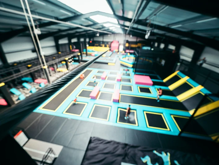 Das Abenteuerland in Bispingen Das Bild zeigt eine große, helle Halle mit verschiedenen Trampolinen in leuchtenden Farben, die zur sportlichen Nutzung angeordnet sind. Bewegung im Hintergrund deutet auf aktive Besucher hin.The picture shows a large, bright hall with various trampolines in bright colors arranged for sports use. Movement in the background indicates active visitors.Billedet viser en stor, lys hal med forskellige trampoliner i stærke farver, der er opstillet til sportslig brug. Bevægelse i baggrunden indikerer aktive besøgende.De foto toont een grote, lichte hal met verschillende trampolines in felle kleuren, opgesteld voor sportief gebruik. Beweging op de achtergrond duidt op actieve bezoekers.