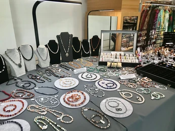 ausstellung-schmuck.jpg Ein eleganter Ausstellungsbereich mit zahlreichen handgefertigten Schmuckstücken, die auf Tischen präsentiert sind.