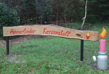 Eingangsschild zum Ammerländer Kerzenstall Holzschild mit roter Schrift Ammerländer Kerzenstall und Kerzendeko auf einer Milchkanne.