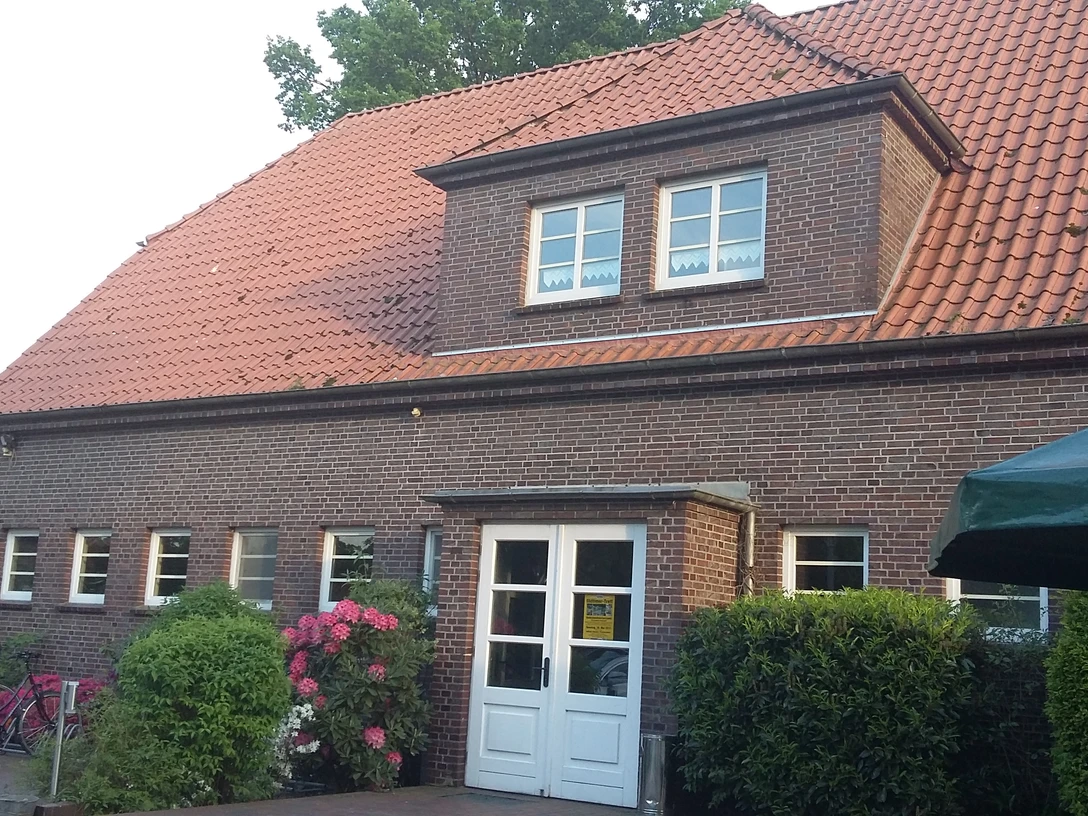 Bokeler Schule (Dörpshus) Das Bild zeigt das historische Backsteingebäude der Bokeler Schule (Dörpshus) mit einem markanten roten Ziegeldach.