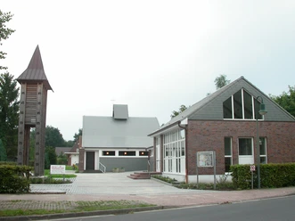 Ev. -luth. Erlöserkirche Leschede Moderne Kirche mit grauem Satteldach und freistehendem hölzernem Glockenturm neben Gemeindehaus.