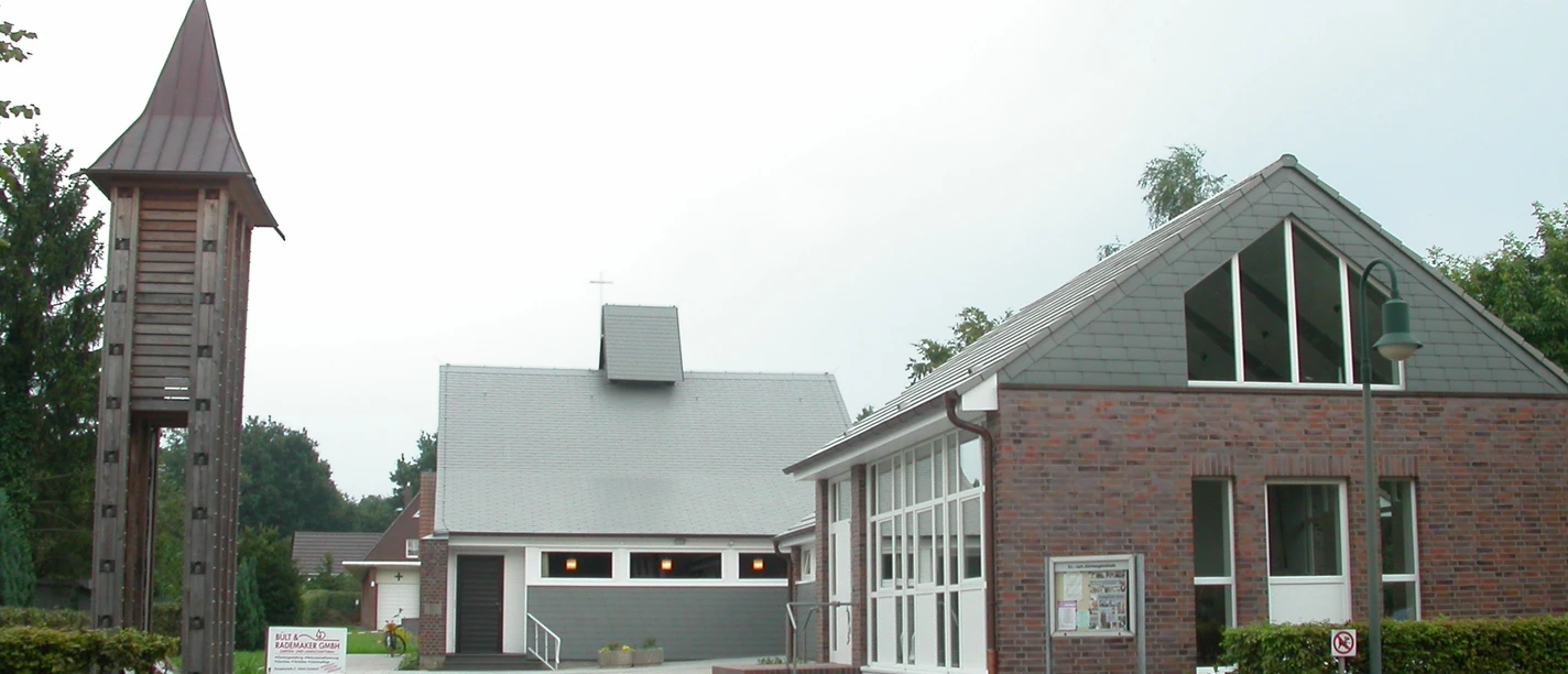 Ev. -luth. Erlöserkirche Leschede Moderne Kirche mit grauem Satteldach und freistehendem hölzernem Glockenturm neben Gemeindehaus.