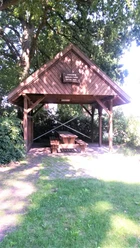 Rastplatz Nordloh Ein hölzerner Pavillon bietet Schutz und beherbergt eine rustikale Sitzgruppe unter knorrigen Bäumen.