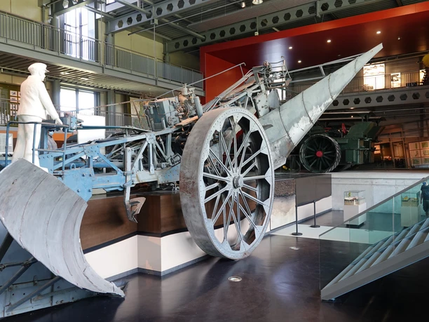 Moormuseum Große historische Moorraupe mit weißen Figuren in moderner Museumshalle aus Stahl und Glas.