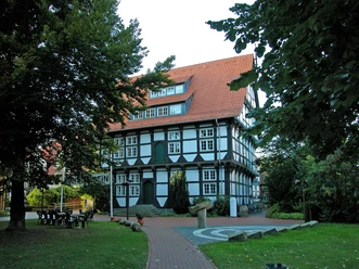 Abtei Wunstorf Fachwerkhaus der Abtei Wunstorf mit rotem Dach, umgeben von Laubbäumen, blauem Himmel im Hintergrund.