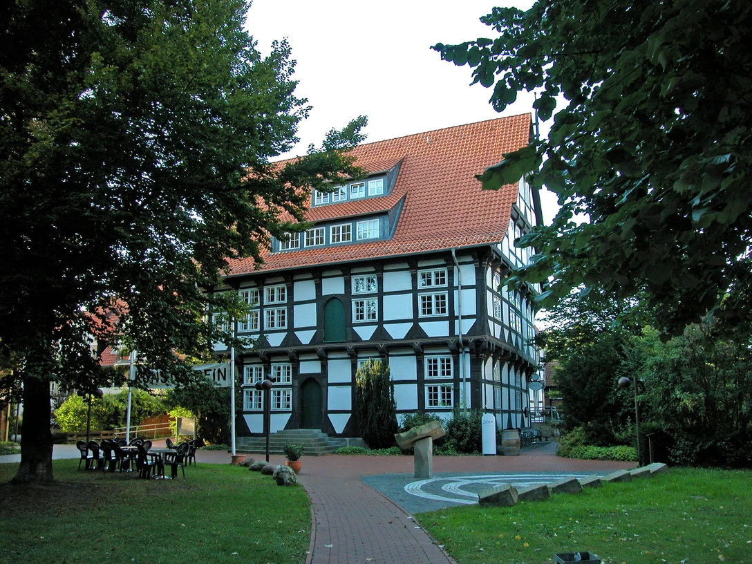 Abtei Wunstorf Fachwerkhaus der Abtei Wunstorf mit rotem Dach, umgeben von Laubbäumen, blauem Himmel im Hintergrund.