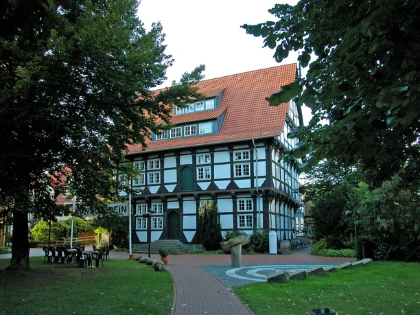 Abtei Wunstorf Fachwerkhaus der Abtei Wunstorf mit rotem Dach, umgeben von Laubbäumen, blauem Himmel im Hintergrund.