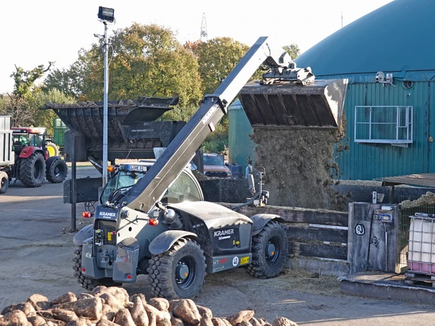 Fahrzeug Hof Engelken Ein Radlader befüllt eine Biogasanlage mit Erntegut, im Hintergrund stehen Traktoren und Anhänger.