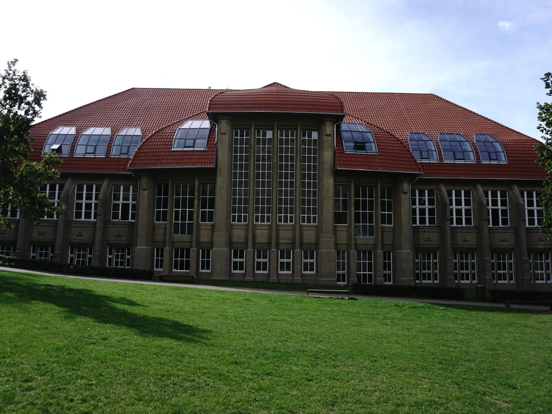 Musik- und Kunstschule Bielefeld Historisches Backsteingebäude mit gewölbtem Dach und großen Fenstern vor grüner Wiese.