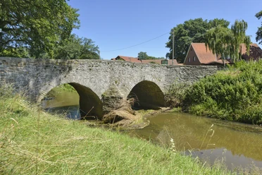 Römerbrücke bei Hunteburg Historische Römerbrücke über die Hunte, umgeben von Wiesen und naturnaher Flusslandschaft.
