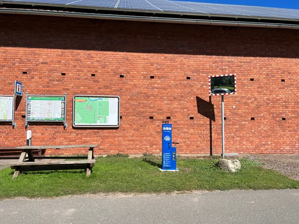 Lufttankstelle Wienbergen Das Bild zeigt eine blaue Lufttankstation vor einer roten Backsteinmauer mit Infotafeln und Spiegel.