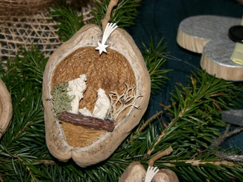 walnuss-krippenspiel Miniatur-Krippenszene in einer geöffneten Walnussschale mit Figuren und kleinem Stern darüber.