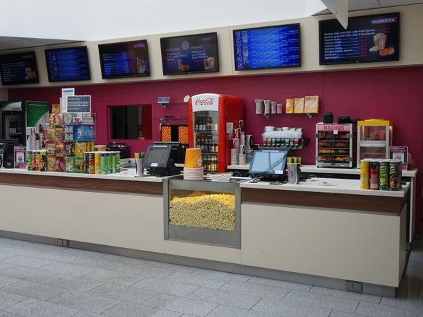 Innenraum Snacktheke mit Popcorn und Nacho-Auswahl, Getränken, Süßigkeiten und digitalen Menübrettern.