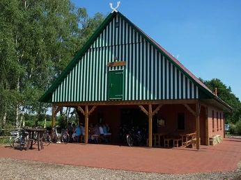 Nordpunkthaus Backsteingebäude mit grünen Fensterläden und Satteldach, umgeben von Fahrrädern und Bäumen.