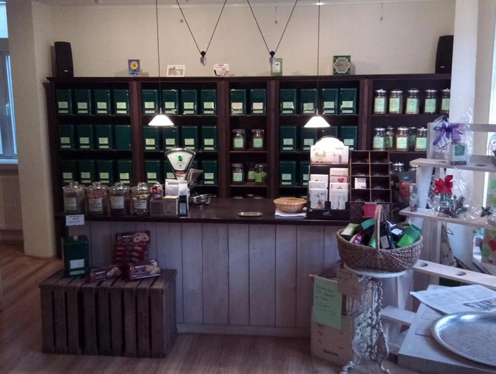 dat-teehus-tee-walsrode Das Bild zeigt das gemütliche Interieur von Dat Teehus in Walsrode. Ein rustikaler Verkaufstresen steht im Vordergrund, eingerahmt von Regalen voller Teedosen in warmen Holztönen. Dezente Beleuchtung und liebevoll arrangierte Dekorationen schaffen eine einladende Atmosphäre. Im Regal sind verschiedene Teesorten sichtbar, die zum Entdecken und Genießen einladen. Der Raum strahlt Wärme und Behaglichkeit aus, ideal für Tee-Liebhaber auf der Suche nach einem besonderen Geschmackserlebnis.