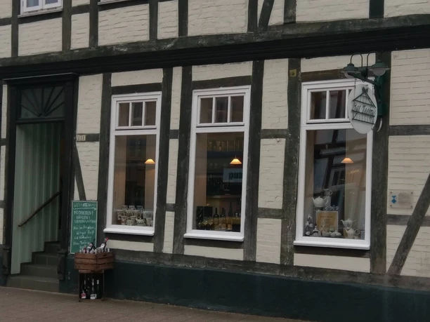 dat-teehus-fachwerk-walsrode Fachwerkgebäude mit dunkelbraunen Balken und weißen Wänden. Dat Teehus-Schild hängt elegant über dem Eingang. Charme einer traditionellen Teestube spürbar.