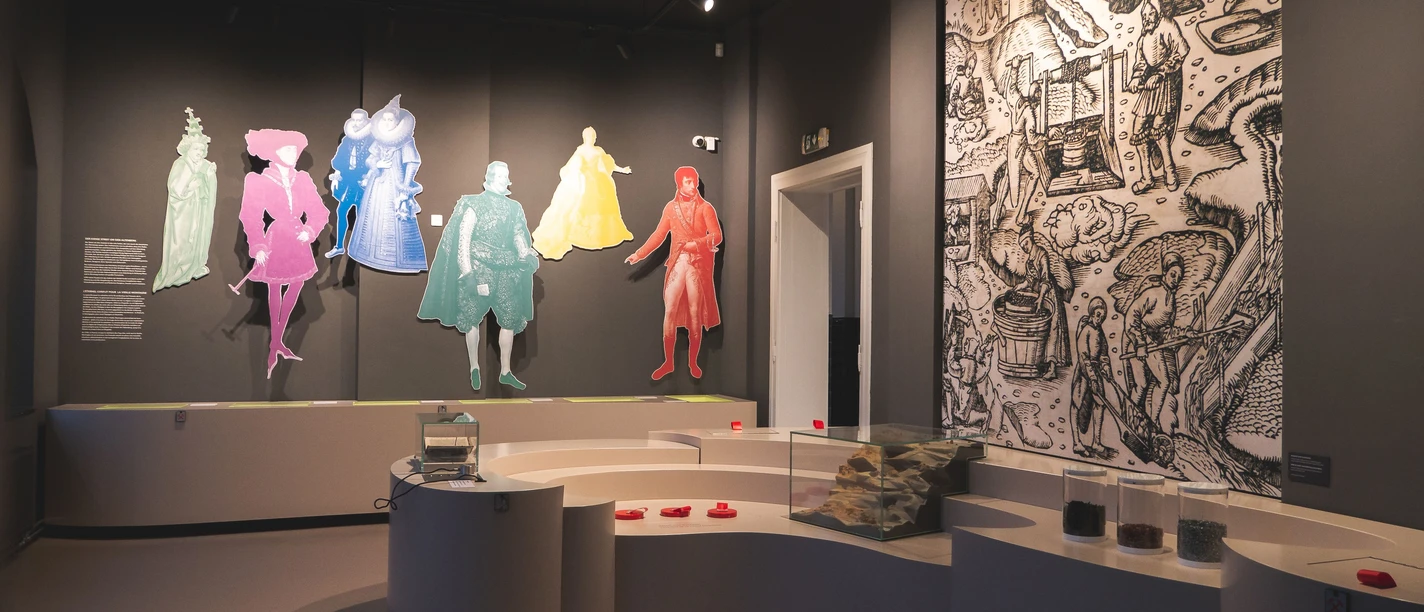 MVM Moderner Museumsraum mit Aufstellern von wichtigen Persönlichkeiten in Aachens Geschichte und einem Tresen mit weiteren Ausstellungsstücken.