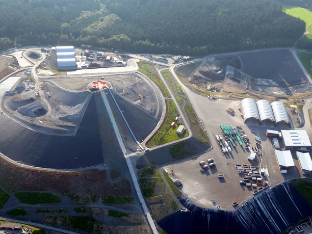 :metabolon - Gärten der Technik Luftaufnahme eines großen Industrie- und Abfallverwertungszentrums, umgeben von Waldlandschaft.