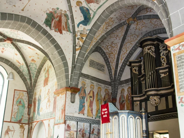 Altar Historische Kapelle mit bemalter Gewölbedecke, farbenfrohen Fresken und einer antiken Orgel.
