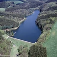 Schevelinger Talsperre Luftaufnahme eines gewundenen Sees, umgeben von dichten Wäldern und grünen Wiesen.