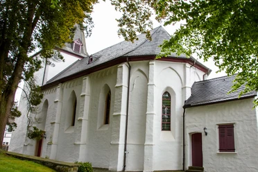 Bonte Kerke Marienhagen Weiß verputzte Kirche mit spitzem Turm, gotischen Fenstern und grüner Umgebung an einem bewölkten Tag.