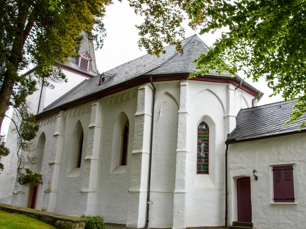Bonte Kerke Marienhagen Weiß verputzte Kirche mit spitzem Turm, gotischen Fenstern und grüner Umgebung an einem bewölkten Tag.