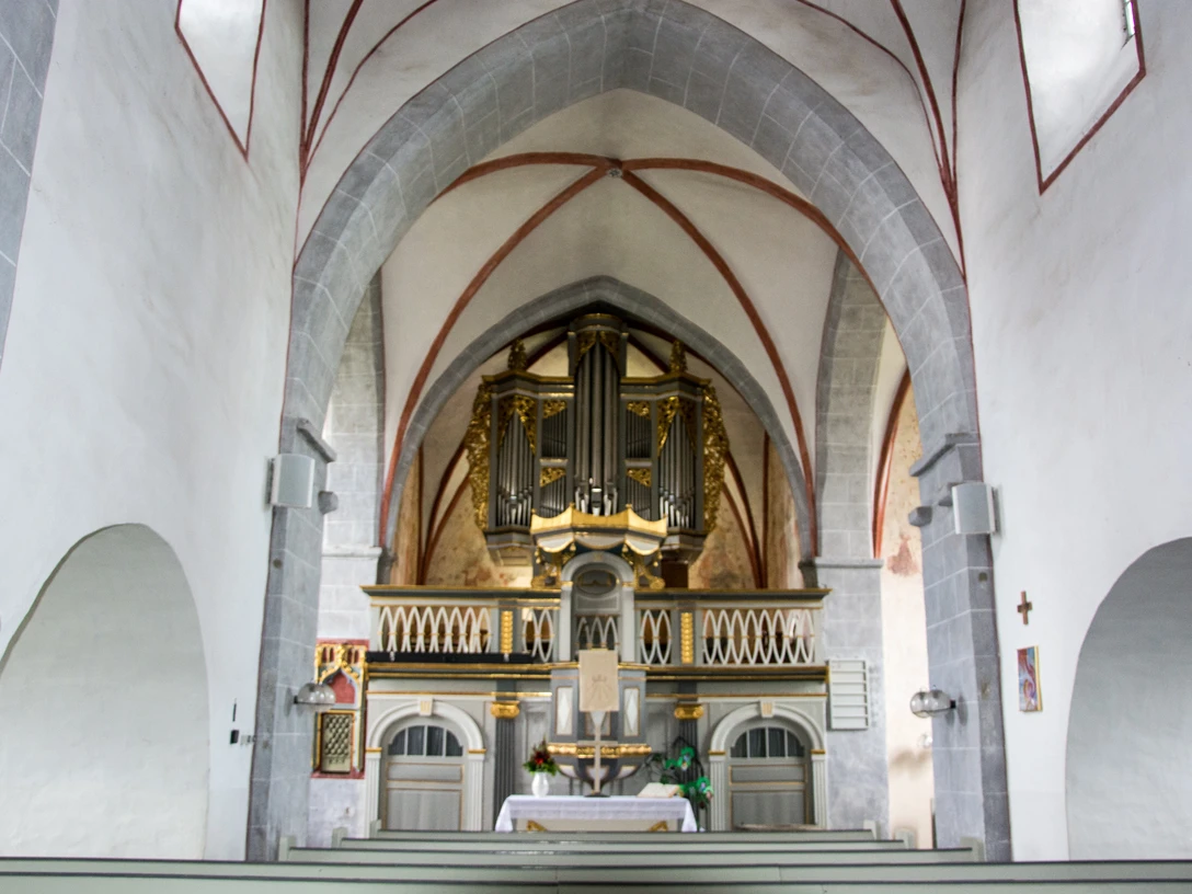 Innenansicht einer gotischen Kirche mit beeindruckender Orgel auf der Empore und hohen Gewölben.